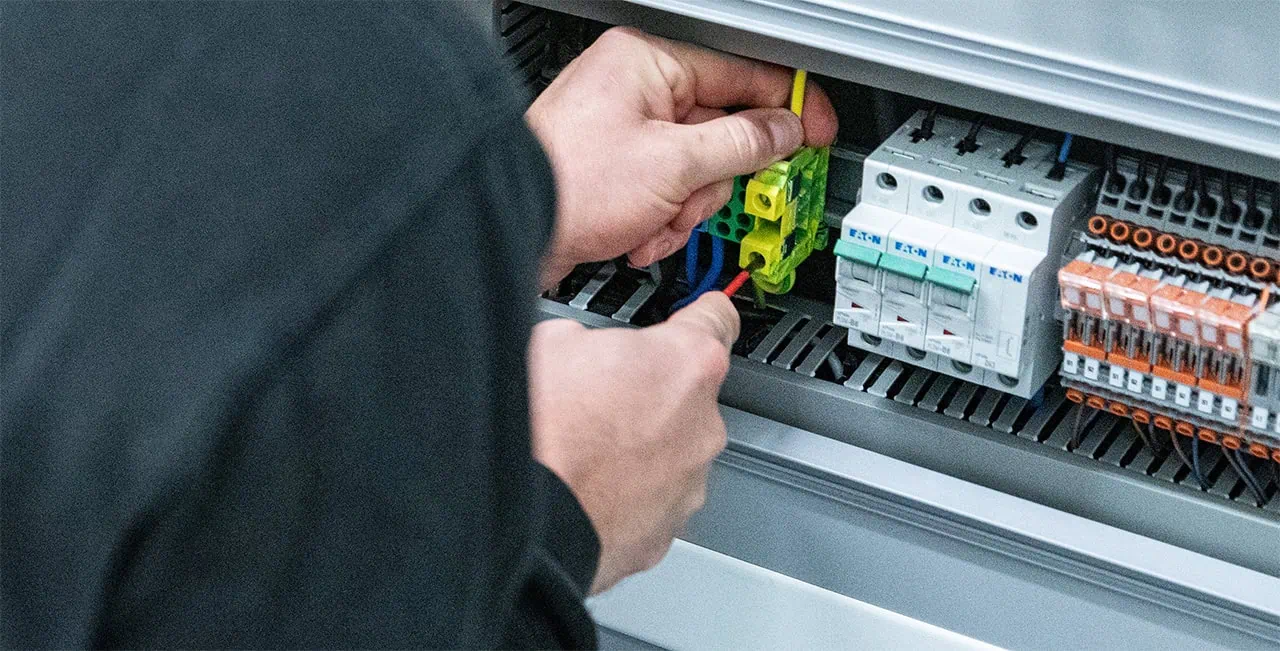 Ein Elektriker der Firma Fuchs befestigt den PE-Leiter in eienr Klemme.